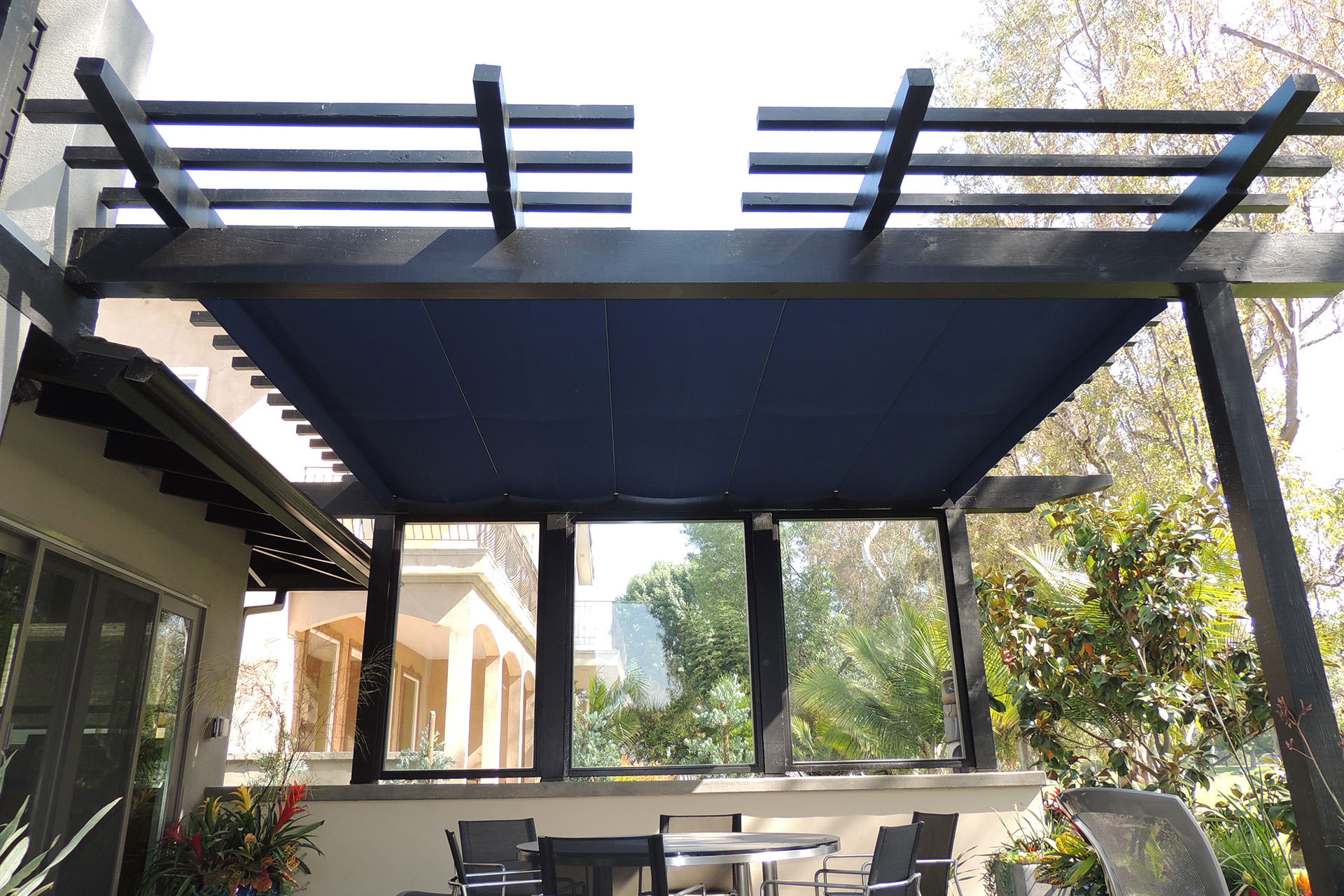 navy blue canopy on a pergola over top an outdoor dining area