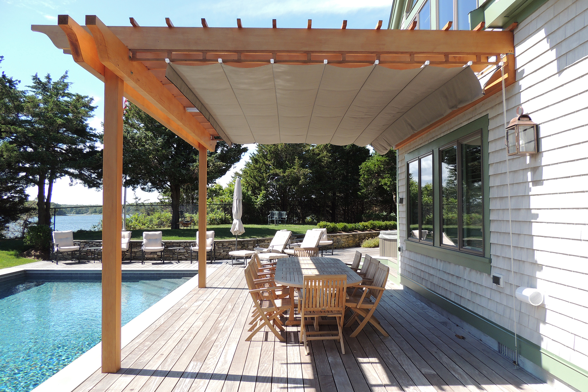 attached wooden pergola and retractable canopy over an outdoor dining area